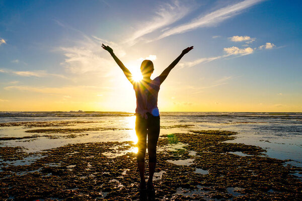 Молодая здоровая женщина практикует йогу на пляже на закате. Сильная доверчивая женщина под закатом на море. Силуэт молодой женщины, занимающейся йогой на пляже
.
