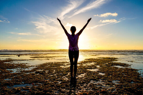 Молодая здоровая женщина практикует йогу на пляже на закате. Сильная доверчивая женщина под закатом на море. Силуэт молодой женщины, занимающейся йогой на пляже
.
