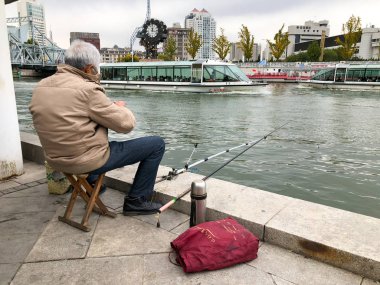 Balıkçı üzerinde merkezinde Tianjin, Çin nehir Haihe çıkabilir. Rıhtımlar üzerinde oturan ve balık yakalamak için bekleyen bir balıkçı. Hobi kavramı