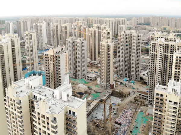 Aerial view of massive building sites in construction with tower crane. Building blocks apartment in construction in developing part of the city of Tianjin in China. Estate construction  site.