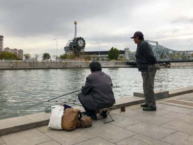 Balıkçı üzerinde merkezinde Tianjin, Çin nehir Haihe çıkabilir. Rıhtımlar üzerinde oturan ve balık yakalamak için bekleyen bir balıkçı. Hobi kavramı