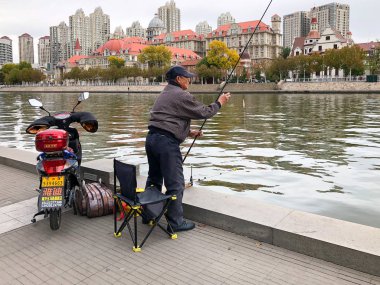 Balıkçı üzerinde merkezinde Tianjin, Çin nehir Haihe çıkabilir. Rıhtımlar üzerinde oturan ve balık yakalamak için bekleyen bir balıkçı. Hobi kavramı