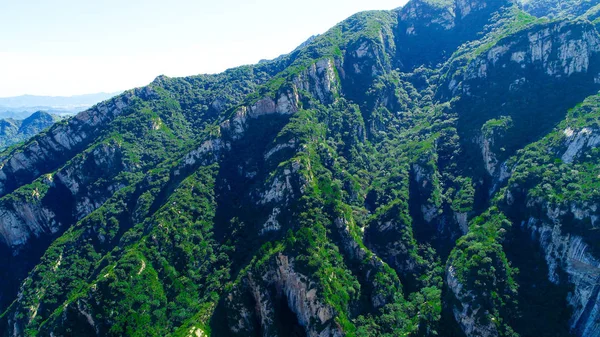Aerial view of green mountain peak with beautiful blue sky and green forest. Landscape of mountain in natural reserve park. Miyun, Beijing, China.