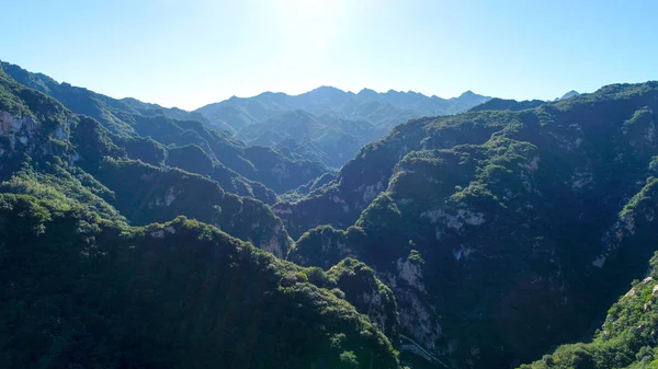 Aerial view of green mountain peak with beautiful blue sky and green forest. Landscape of mountain in natural reserve park. Miyun, Beijing, China.