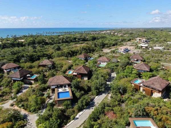 Aerial view of luxury villa with swimming pool in tropical forest. Private tropical villa with swimming pool among tropical garden with palm trees with blue sea and coast on the background. Praia de Forte, Bahia, Brazil