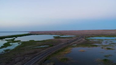 Günbatımı sırasında Sincan Uygur Özerk Bölgesi, Çin içinde çöl sonraki Ailik veya aylık gölün ortasındaki boş bir yolda araba havadan görünümü.