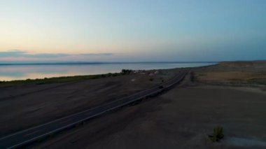 Günbatımı sırasında Sincan Uygur Özerk Bölgesi, Çin içinde çöl sonraki Ailik veya aylık gölün ortasındaki boş bir yolda araba havadan görünümü.