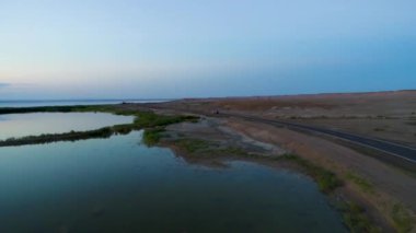 Günbatımı sırasında Sincan Uygur Özerk Bölgesi, Çin içinde çöl sonraki Ailik veya aylık gölün ortasındaki boş bir yolda araba havadan görünümü.
