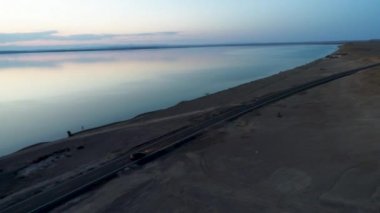 Günbatımı sırasında Sincan Uygur Özerk Bölgesi, Çin içinde çöl sonraki Ailik veya aylık gölün ortasındaki boş bir yolda araba havadan görünümü.