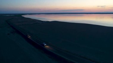 Günbatımı sırasında Sincan Uygur Özerk Bölgesi, Çin içinde çöl sonraki Ailik veya aylık gölün ortasındaki boş bir yolda araba havadan görünümü.