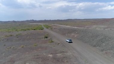 Sincan Uygur Özerk Bölgesi, Çin çöl sonraki Ailik gölün ortasındaki boş bir yolda araba araba hava görünümünü. kurak, tozlu bir yolda araba 4 x 4 arazi çöl 08/24/2018