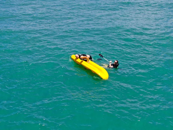在清澈的蓝色碧绿海水上 有强壮的年轻活跃男子用皮划艇的鸟瞰图 活动假期 普拉亚多福特 — 图库照片