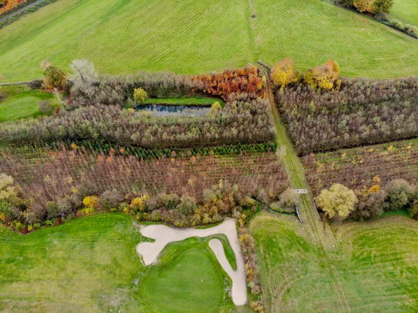 Aerial view of a golf course. Beautiful colorful trees and green course during autumn/winter season in the South of Belgium, Walloon Brabant.