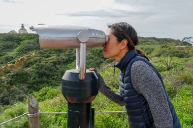 San Diego, Kaliforniya, ABD noktası Loma Yarımadası'nın uç üzerinde dürbün teleskop içinde arıyorsunuz Asya sportif kadın. San Diego şehir ve bay gözlemlemek için otomatik dürbün arayan genç kadın. işletilen sikke dürbün.