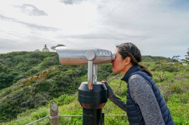 San Diego, Kaliforniya, ABD noktası Loma Yarımadası'nın uç üzerinde dürbün teleskop içinde arıyorsunuz Asya sportif kadın. San Diego şehir ve bay gözlemlemek için otomatik dürbün arayan genç kadın. işletilen sikke dürbün.
