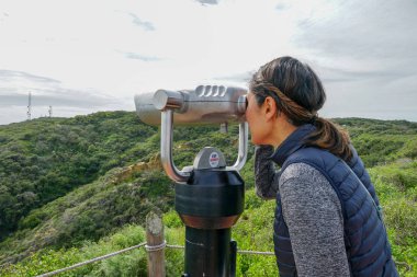 San Diego, Kaliforniya, ABD noktası Loma Yarımadası'nın uç üzerinde dürbün teleskop içinde arıyorsunuz Asya sportif kadın. San Diego şehir ve bay gözlemlemek için otomatik dürbün arayan genç kadın. işletilen sikke dürbün.