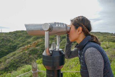 San Diego, Kaliforniya, ABD noktası Loma Yarımadası'nın uç üzerinde dürbün teleskop içinde arıyorsunuz Asya sportif kadın. San Diego şehir ve bay gözlemlemek için otomatik dürbün arayan genç kadın. işletilen sikke dürbün.