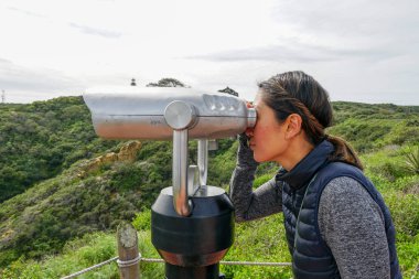 San Diego, Kaliforniya, ABD noktası Loma Yarımadası'nın uç üzerinde dürbün teleskop içinde arıyorsunuz Asya sportif kadın. San Diego şehir ve bay gözlemlemek için otomatik dürbün arayan genç kadın. işletilen sikke dürbün.