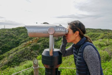 San Diego, Kaliforniya, ABD noktası Loma Yarımadası'nın uç üzerinde dürbün teleskop içinde arıyorsunuz Asya sportif kadın. San Diego şehir ve bay gözlemlemek için otomatik dürbün arayan genç kadın. işletilen sikke dürbün.