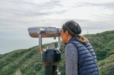 San Diego, Kaliforniya, ABD noktası Loma Yarımadası'nın uç üzerinde dürbün teleskop içinde arıyorsunuz Asya sportif kadın. San Diego şehir ve bay gözlemlemek için otomatik dürbün arayan genç kadın. işletilen sikke dürbün.