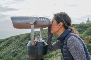 San Diego, Kaliforniya, ABD noktası Loma Yarımadası'nın uç üzerinde dürbün teleskop içinde arıyorsunuz Asya sportif kadın. San Diego şehir ve bay gözlemlemek için otomatik dürbün arayan genç kadın. işletilen sikke dürbün.