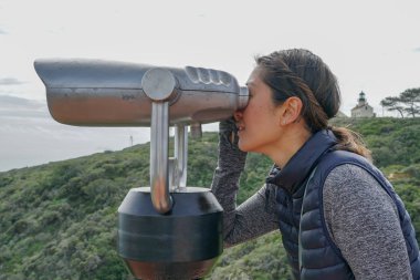 San Diego, Kaliforniya, ABD noktası Loma Yarımadası'nın uç üzerinde dürbün teleskop içinde arıyorsunuz Asya sportif kadın. San Diego şehir ve bay gözlemlemek için otomatik dürbün arayan genç kadın. işletilen sikke dürbün.