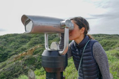 San Diego, Kaliforniya, ABD noktası Loma Yarımadası'nın uç üzerinde dürbün teleskop içinde arıyorsunuz Asya sportif kadın. San Diego şehir ve bay gözlemlemek için otomatik dürbün arayan genç kadın. işletilen sikke dürbün.