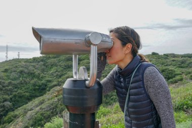 San Diego, Kaliforniya, ABD noktası Loma Yarımadası'nın uç üzerinde dürbün teleskop içinde arıyorsunuz Asya sportif kadın. San Diego şehir ve bay gözlemlemek için otomatik dürbün arayan genç kadın. işletilen sikke dürbün.