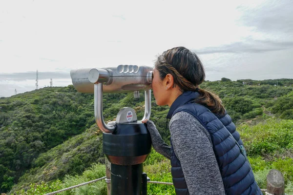San Diego, Kaliforniya, ABD noktası Loma Yarımadası'nın uç üzerinde dürbün teleskop içinde arıyorsunuz Asya sportif kadın. San Diego şehir ve bay gözlemlemek için otomatik dürbün arayan genç kadın. işletilen sikke dürbün.