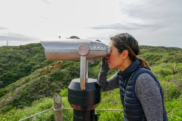 San Diego, Kaliforniya, ABD noktası Loma Yarımadası'nın uç üzerinde dürbün teleskop içinde arıyorsunuz Asya sportif kadın. San Diego şehir ve bay gözlemlemek için otomatik dürbün arayan genç kadın. işletilen sikke dürbün.