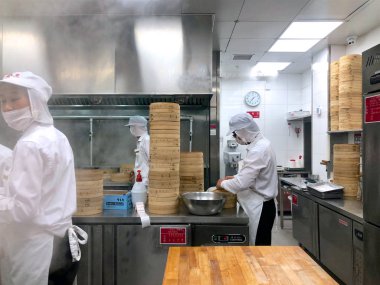 Şefler tarafından bir restoranda geleneksel bambu vapurları Çin köfte yemek vardır. Dim Sum şefler sarma mantı ünlü restoranda Din Tai Fung çalışma. Pekin, Çin. 09/10/2018