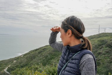 Genç sporcu Asyalı kadın güzel okyanus manzarasına bakıyor. Yürüyüş yapan genç bir kadın manzaraya hayran. sağlıklı aktif yaşam biçimi.