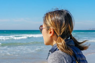Asya'da yaz aylarında plajmanzarasına bakan sportif genç kadın. Sahilde denizden bakan güzel bir kız. ilham verici an. Ufka bakan genç bir kadının portresi