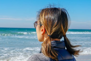 Asya'da yaz aylarında plajmanzarasına bakan sportif genç kadın. Sahilde denizden bakan güzel bir kız. ilham verici an. Ufka bakan genç bir kadının portresi