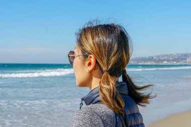 Asya'da yaz aylarında plajmanzarasına bakan sportif genç kadın. Sahilde denizden bakan güzel bir kız. ilham verici an. Ufka bakan genç bir kadının portresi