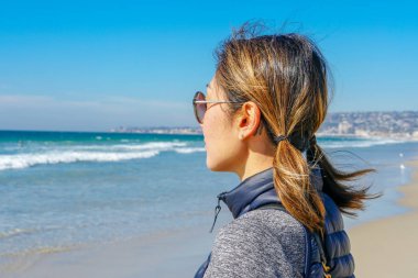 Asya'da yaz aylarında plajmanzarasına bakan sportif genç kadın. Sahilde denizden bakan güzel bir kız. ilham verici an. Ufka bakan genç bir kadının portresi