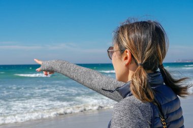 Asya'da yaz aylarında plajmanzarasına bakan sportif genç kadın. Sahilde denizden bakan güzel bir kız. ilham verici an. Ufka bakan genç bir kadının portresi