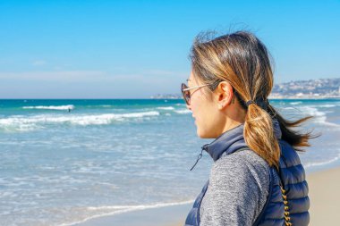 Asya'da yaz aylarında plajmanzarasına bakan sportif genç kadın. Sahilde denizden bakan güzel bir kız. ilham verici an. Ufka bakan genç bir kadının portresi