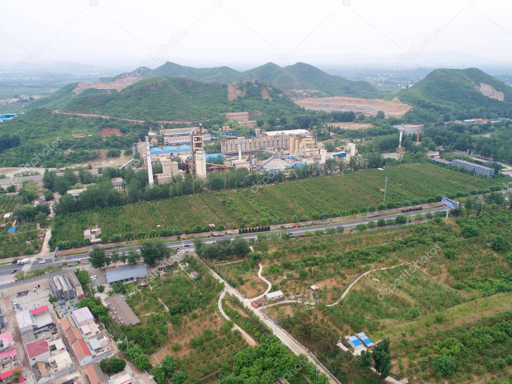 Aerial view of factory in the middle of thr mountain and green farm land, in the area of Huaibei, China. Industrial factory, pollution.