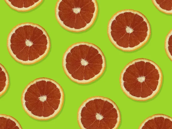 Creative pattern made of red oranges. top view of colorful fruit pattern of fresh red orange slices on green colorful background.