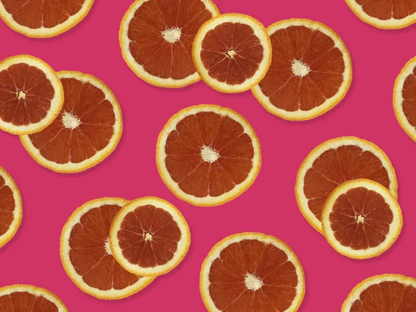 Creative pattern made of red oranges. top view of colorful fruit pattern of fresh red orange slices on pink colorful background.