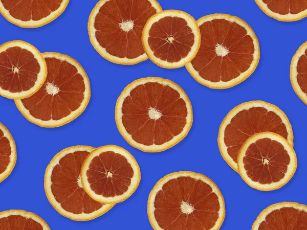 Creative pattern made of red oranges. top view of colorful fruit pattern of fresh red orange slices on purple colorful background.
