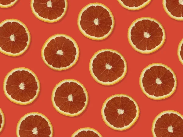 Creative pattern made of red oranges. top view of colorful fruit pattern of fresh red orange slices on orange colorful background.