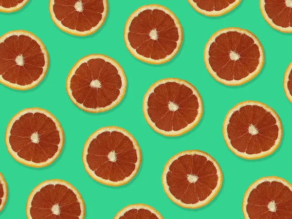Creative pattern made of red oranges. top view of colorful fruit pattern of fresh red orange slices on green colorful background.