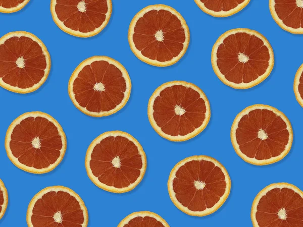 Creative pattern made of red oranges. top view of colorful fruit pattern of fresh red orange slices on purple colorful background.