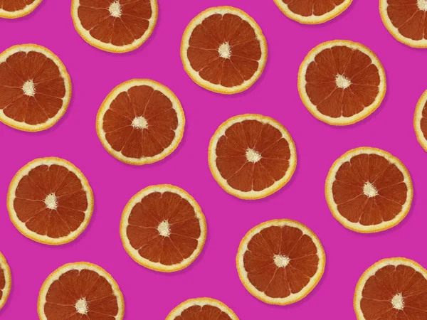 Creative pattern made of red oranges. top view of colorful fruit pattern of fresh red orange slices on pink colorful background.