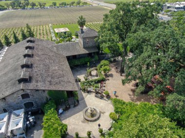 V. Sattui Winery ve perakende mağaza, St Helena, Napa Vadisi, Kaliforniya, ABD havadan görünümü. Üzüm bağları ile çevrili yeşil bahçede içki ve düğün etkinliğine sahip insanlar