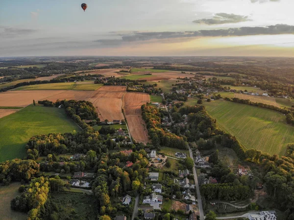 Hot air balloons in the sky of Walloon over beautiful farmland landscape. Colorful hot air balloons flying over the valley during  sunset time. Belgium