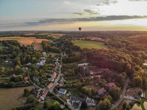 Hot air balloons in the sky of Walloon over beautiful farmland landscape. Colorful hot air balloons flying over the valley during  sunset time. Belgium