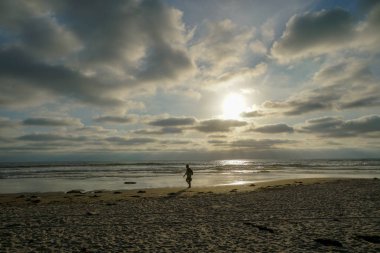 Gün batımı huzurlu an sırasında zevk ve yürüyüş insanların silüeti. Alacakaranlık zaman ve deniz üzerinde yansıma güzel gökyüzü. La Jolla, San Diego, Kaliforniya, ABD